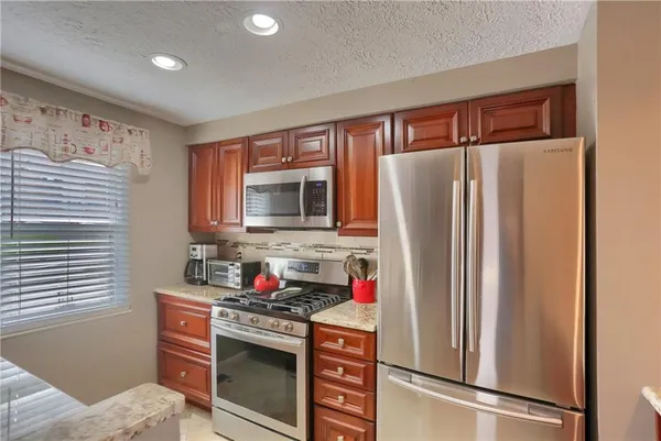a kitchen with granite countertop a refrigerator and microwave