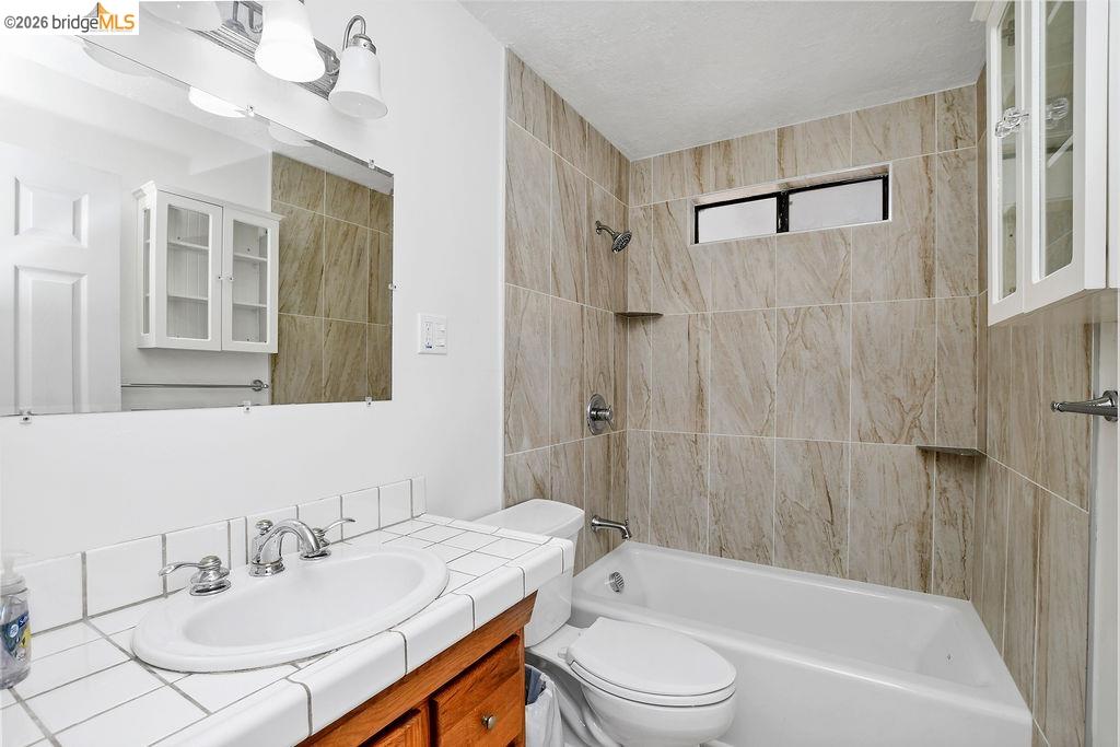 805 Calero Street Milpitas, CA 95035 - Photo 10 of 23 Bathroom featuring a tiled shower surround, recessed window, white bathtub, and vanity with an integrated sink and tiled countertop