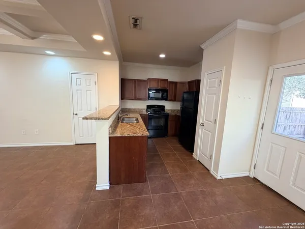 a kitchen with kitchen island granite countertop a refrigerator oven a sink a stove and cabinets