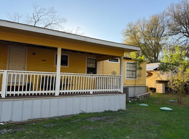 a view of a backyard with couches plants and large trees