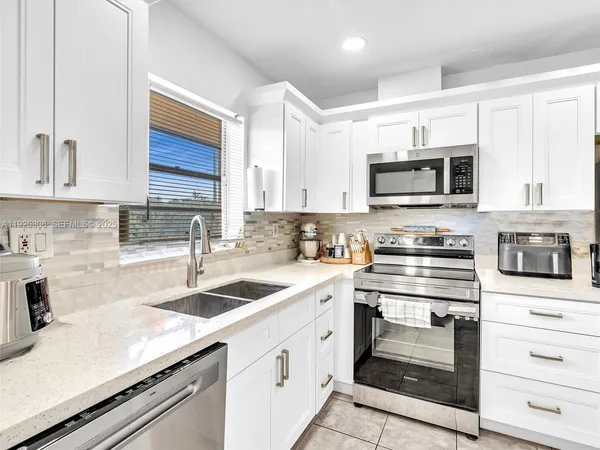 a kitchen with cabinets appliances a sink and a counter top space