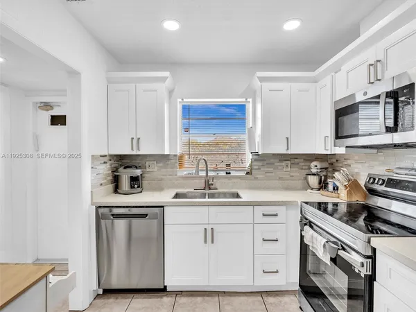 a kitchen with white cabinets stainless steel appliances and sink