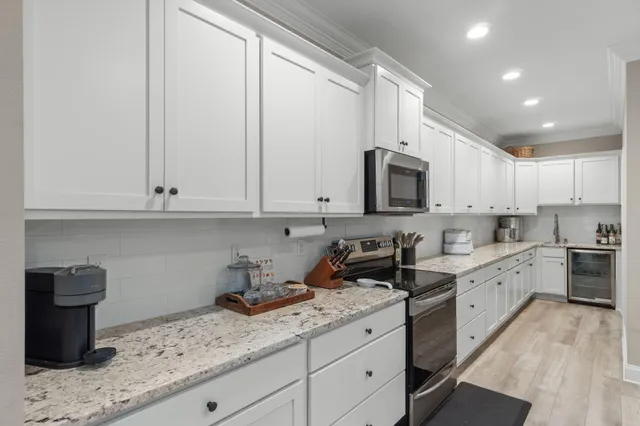 a kitchen with granite countertop white cabinets white stainless steel appliances and a sink
