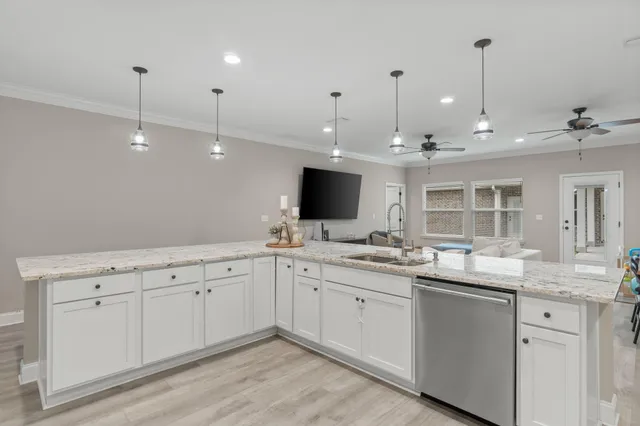 a large white kitchen with a sink and dishwasher with white cabinets