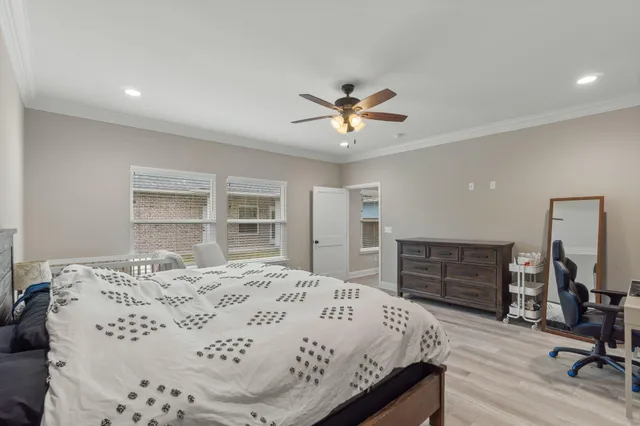 a bedroom with a bed a dresser and wooden floor