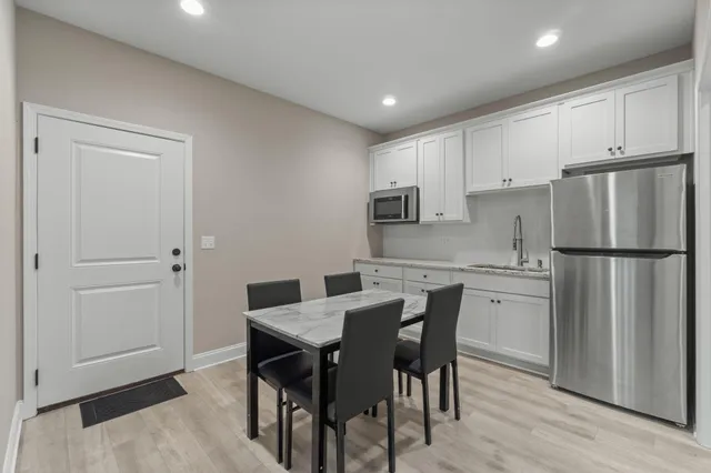 a kitchen with stainless steel appliances granite countertop a dining table chairs refrigerator and cabinets
