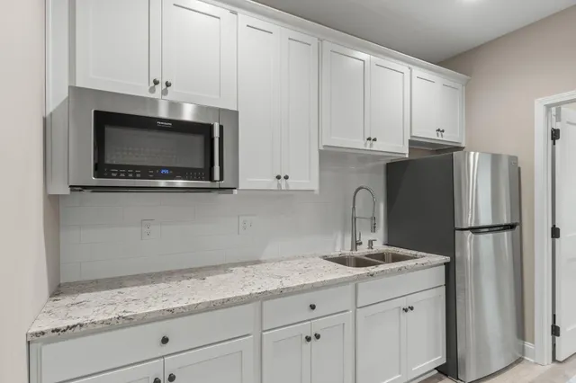 a kitchen with granite countertop white cabinets and stainless steel appliances