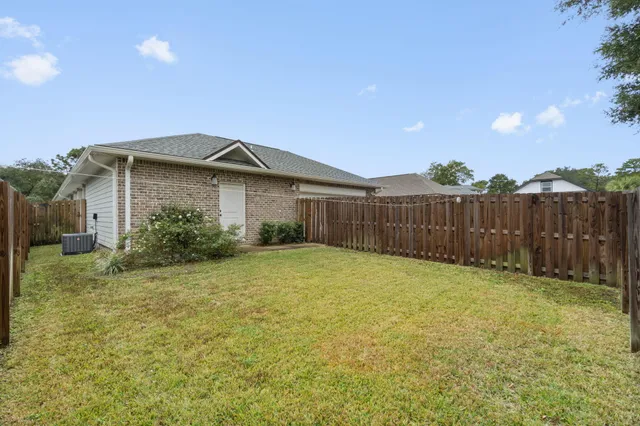 a yellow house with a big yard and wooden fence