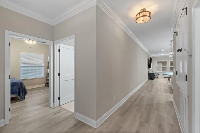 a view of a hallway with wooden floor and a bathroom
