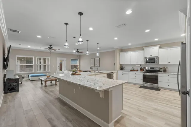 a large kitchen with kitchen island a stove a refrigerator a sink dishwasher a dining table and chairs with wooden floor