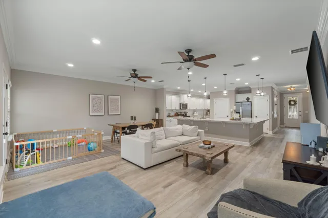 a living room with furniture kitchen view and a wooden floor