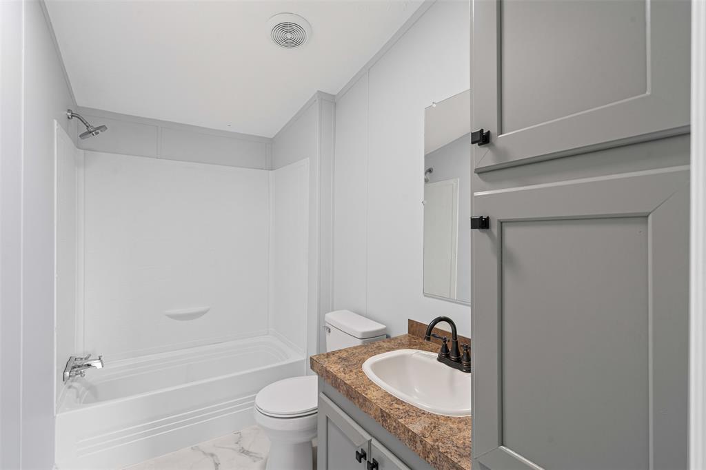 430 Indian Hills Road Bowie, TX 76230 - Photo 11 of 36 a bathroom with a granite countertop sink toilet and shower