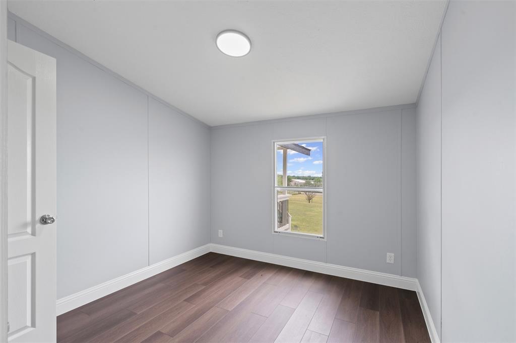 430 Indian Hills Road Bowie, TX 76230 - Photo 14 of 36 an empty room with wooden floor and windows