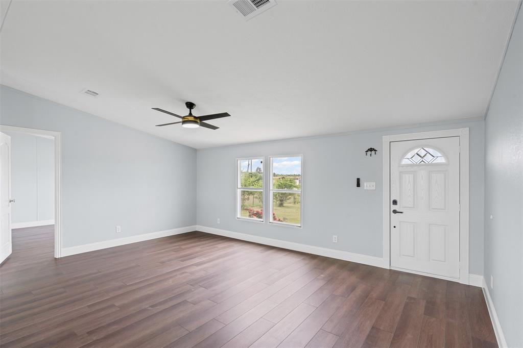 430 Indian Hills Road Bowie, TX 76230 - Photo 5 of 36 an empty room with wooden floor a ceiling fan and windows