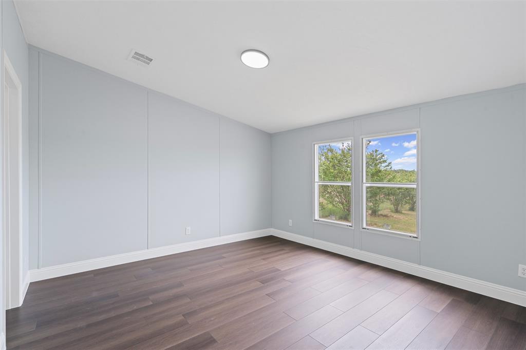 430 Indian Hills Road Bowie, TX 76230 - Photo 7 of 36 a view of an empty room with wooden floor and a window