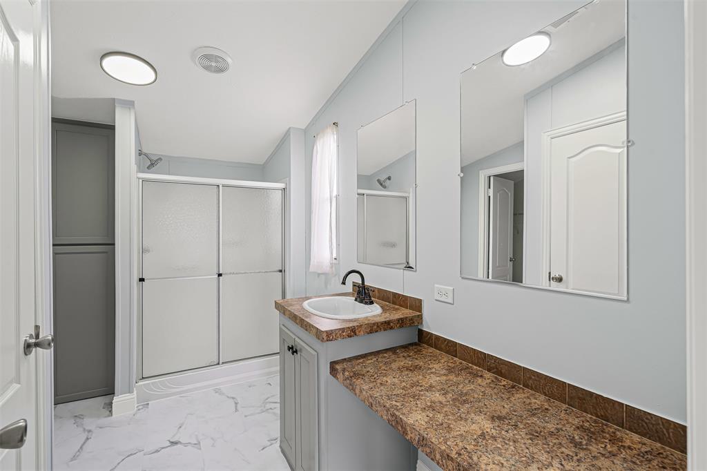 430 Indian Hills Road Bowie, TX 76230 - Photo 9 of 36 a bathroom with a granite countertop sink and a mirror