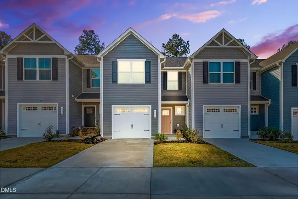 a front view of a house with yard and parking