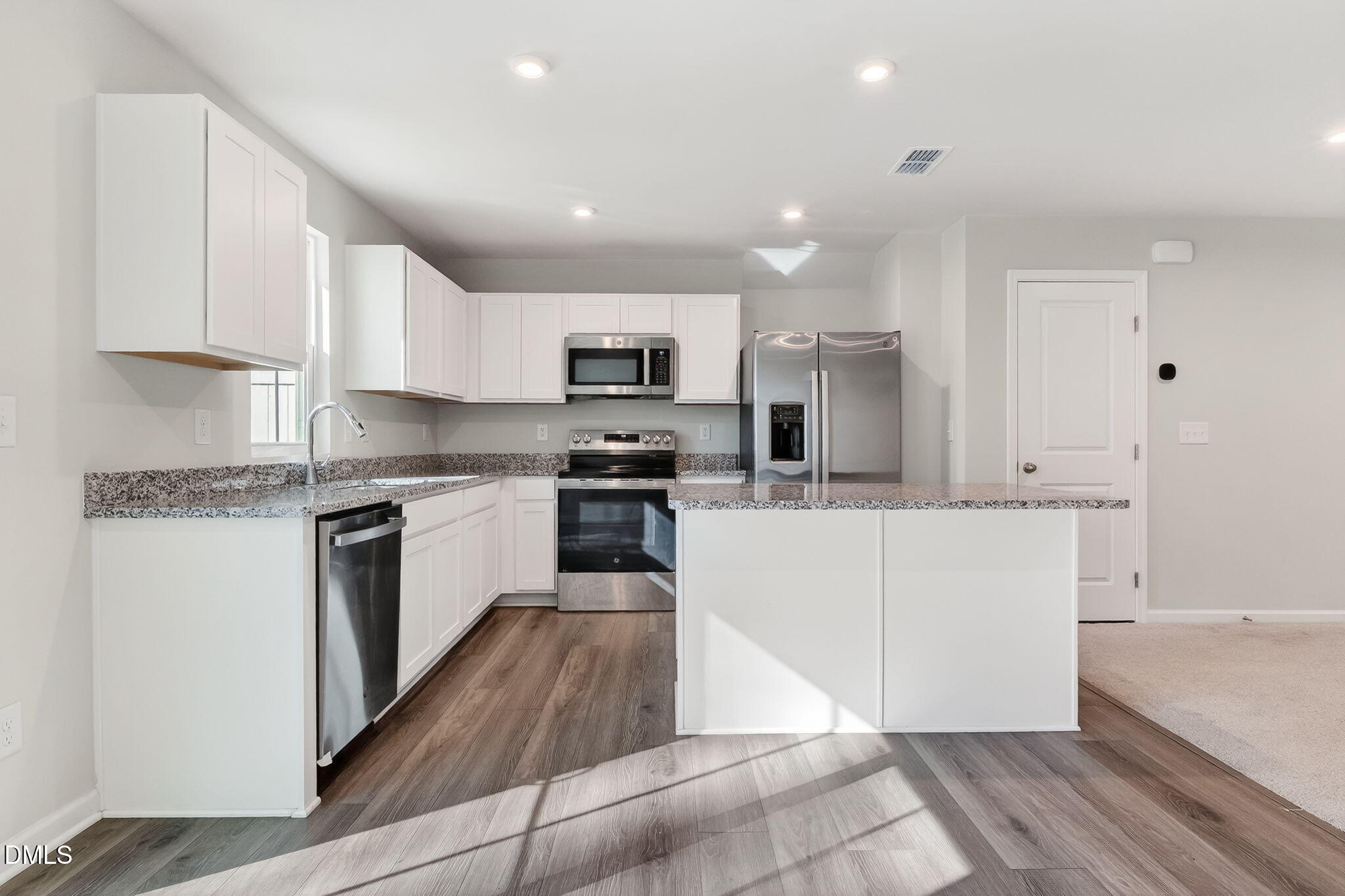 6684 Gibraltar Rock Drive Raleigh, NC 27610 - Photo 10 of 33 a kitchen with kitchen island a stove a sink a refrigerator and a microwave