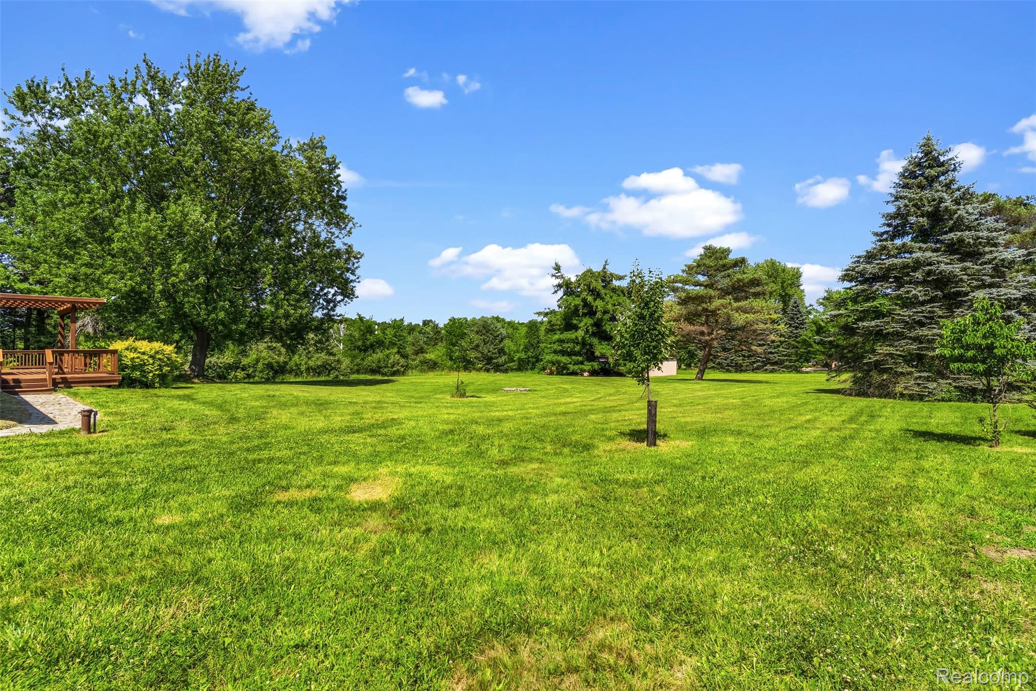 9200 Hickory Ridge Road Holly, MI 48442 - Photo 25 of 33 Expansive green lawn with mature trees and a wooden deck featuring a pergola