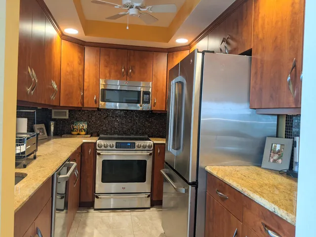 a kitchen with stainless steel appliances granite countertop a stove a sink and a refrigerator
