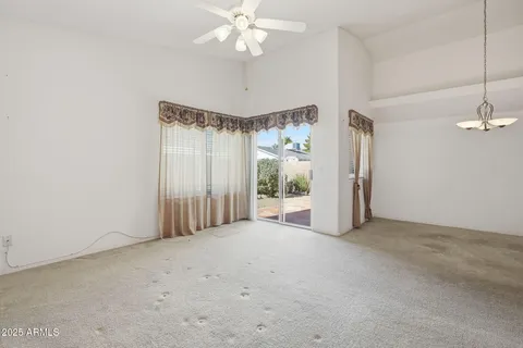 an empty room with windows and chandelier fan