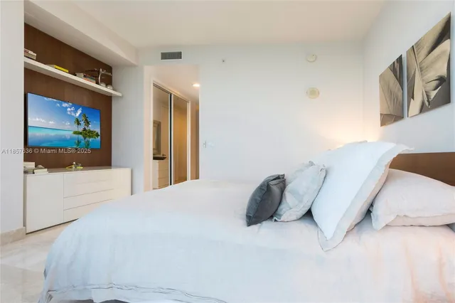 a spacious bedroom with a bed and a flat screen tv