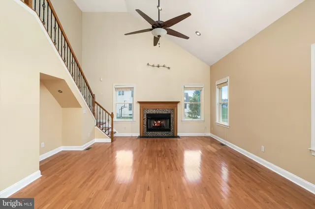 a view of an empty room with wooden floor fireplace and a window