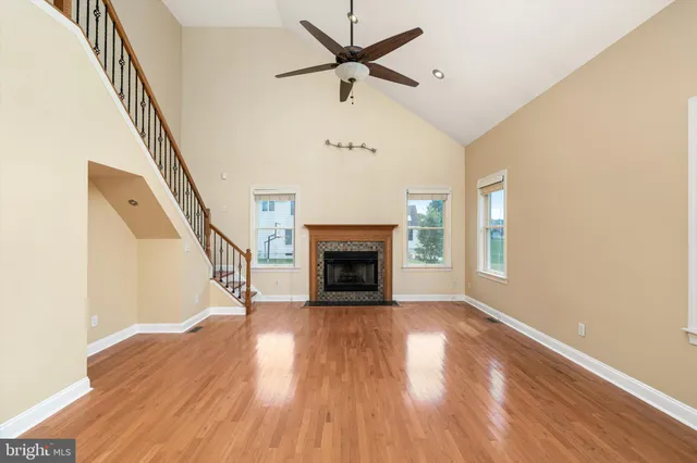 a view of an empty room with wooden floor fireplace and a window