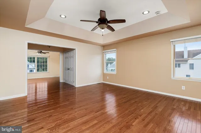 a view of empty room with wooden floor and fan