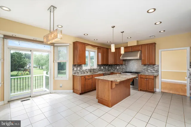 a large kitchen with granite countertop a stove a sink and a refrigerator