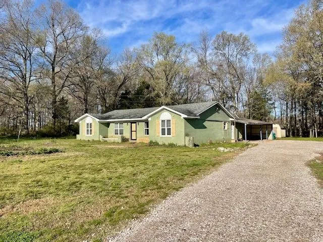 a front of a house with a garden and trees