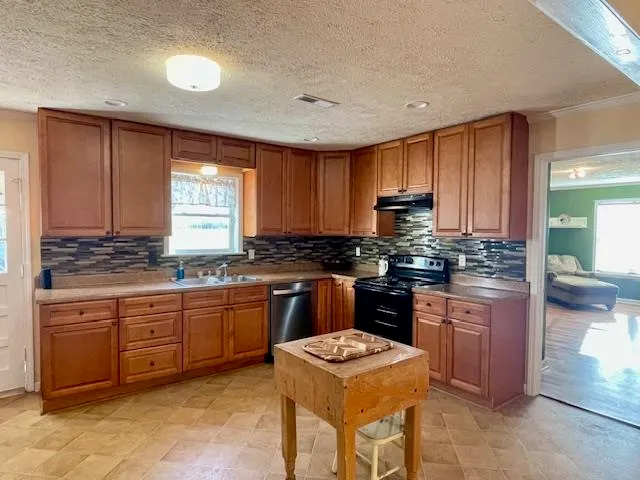 a kitchen with kitchen island granite countertop wooden cabinets a stove a sink and a window