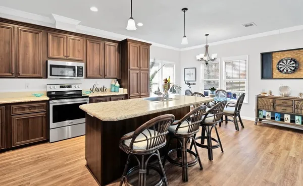 a kitchen with granite countertop stainless steel appliances cabinets wooden floor and view living room