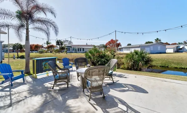 a view of a patio with table and chairs potted plants and palm tree
