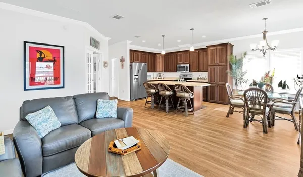 a living room with furniture kitchen view and a chandelier