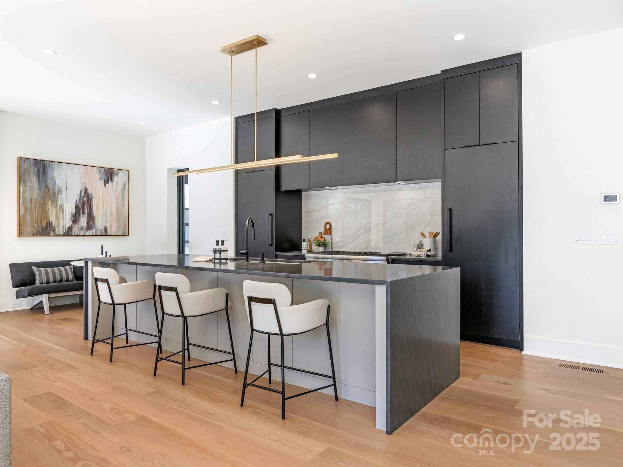 2832 Arcadia Avenue Charlotte, NC 28209 - Photo 12 of 48 a kitchen with stainless steel appliances kitchen island a table chairs in it and wooden floors