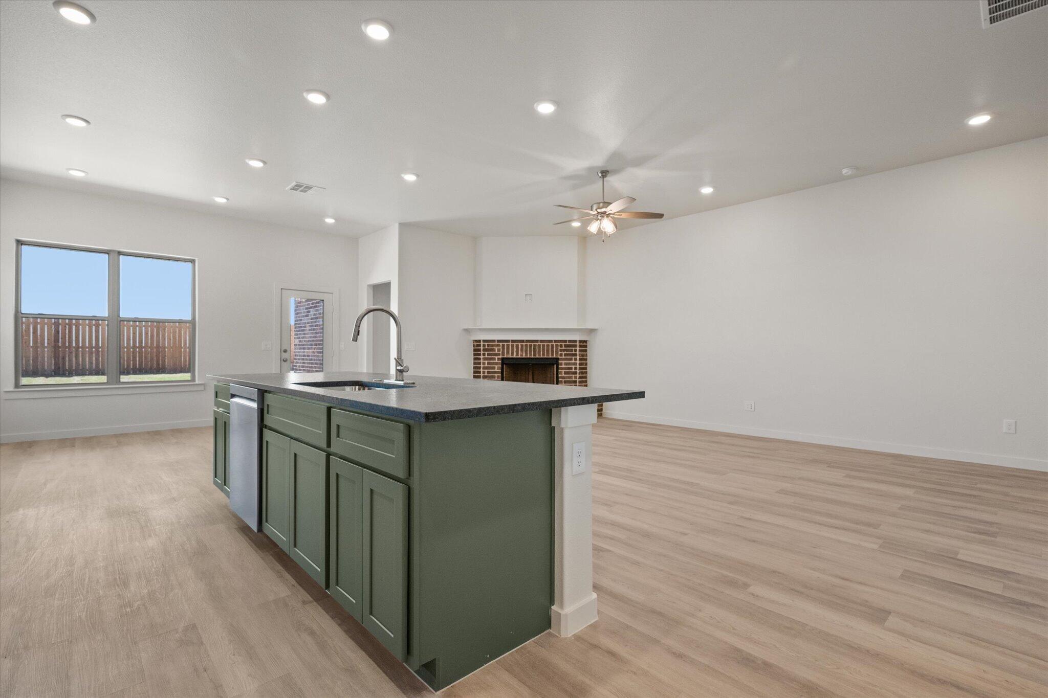6105 121st Street Lubbock, TX 79424 - Photo 12 of 24 a kitchen with stainless steel appliances granite countertop a sink and stove top oven with wooden floor