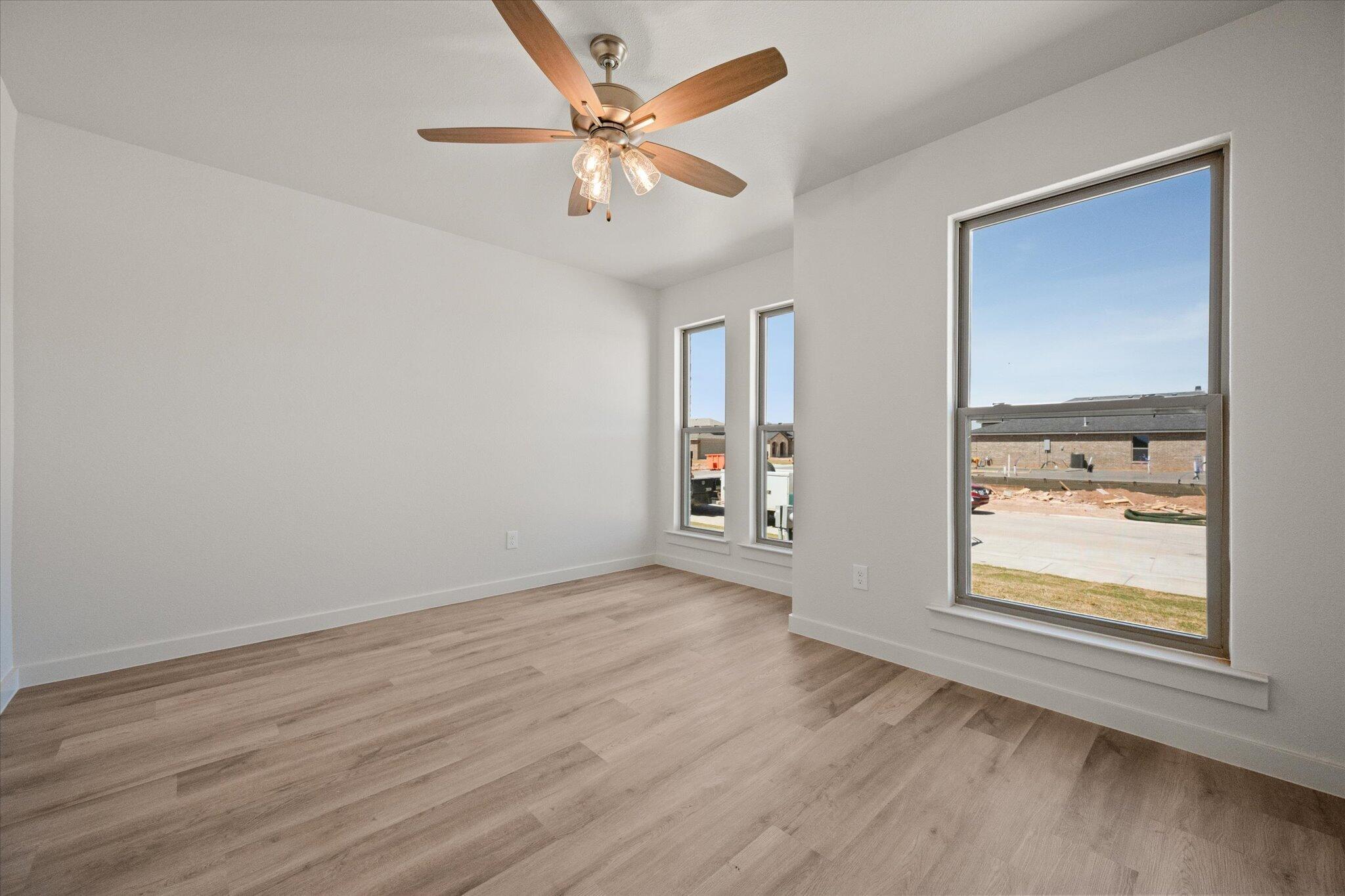 6105 121st Street Lubbock, TX 79424 - Photo 20 of 24 an empty room with wooden floor chandelier fan and windows