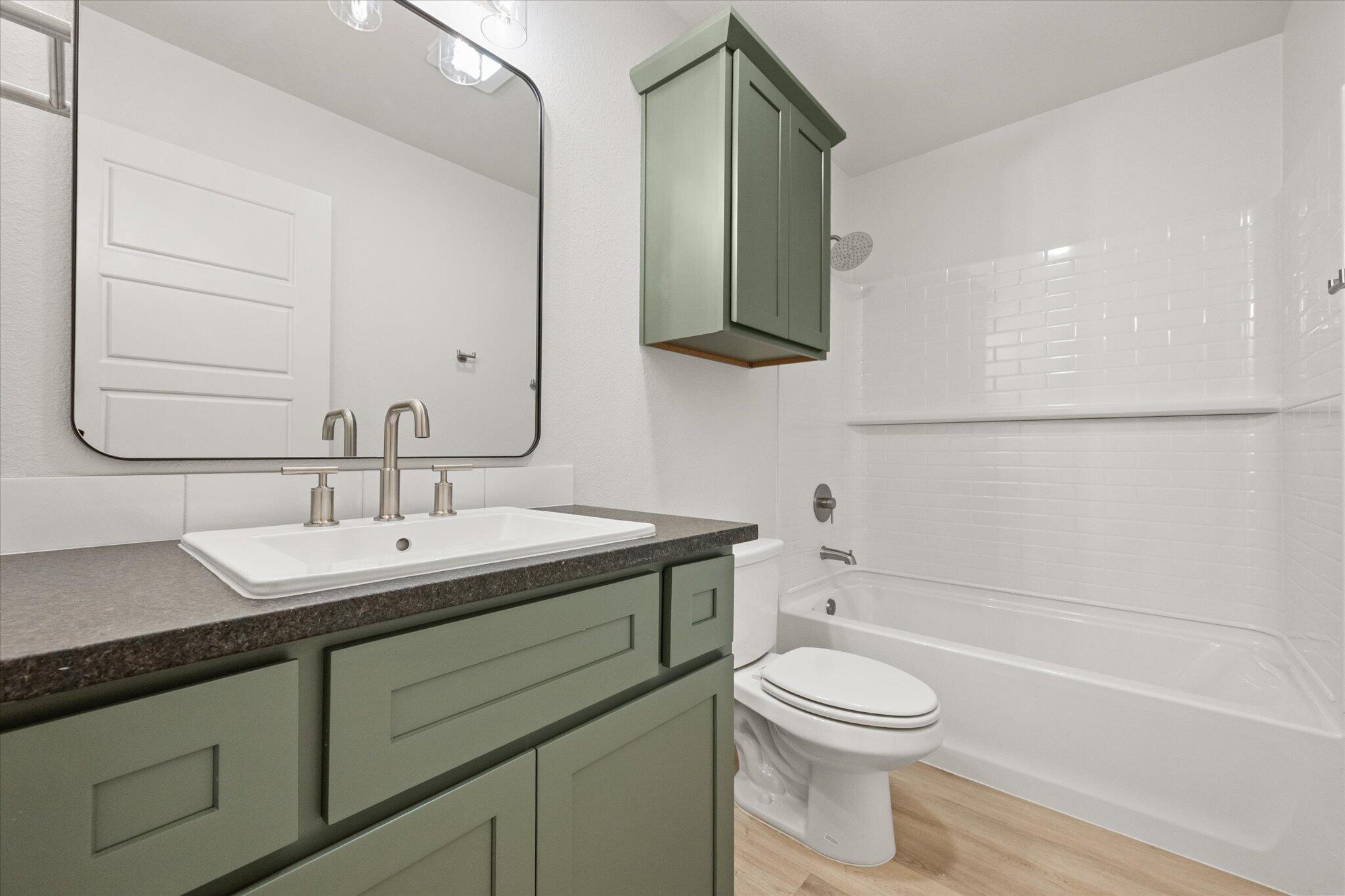 6105 121st Street Lubbock, TX 79424 - Photo 22 of 24 a bathroom with a toilet a sink a mirror and bathtub