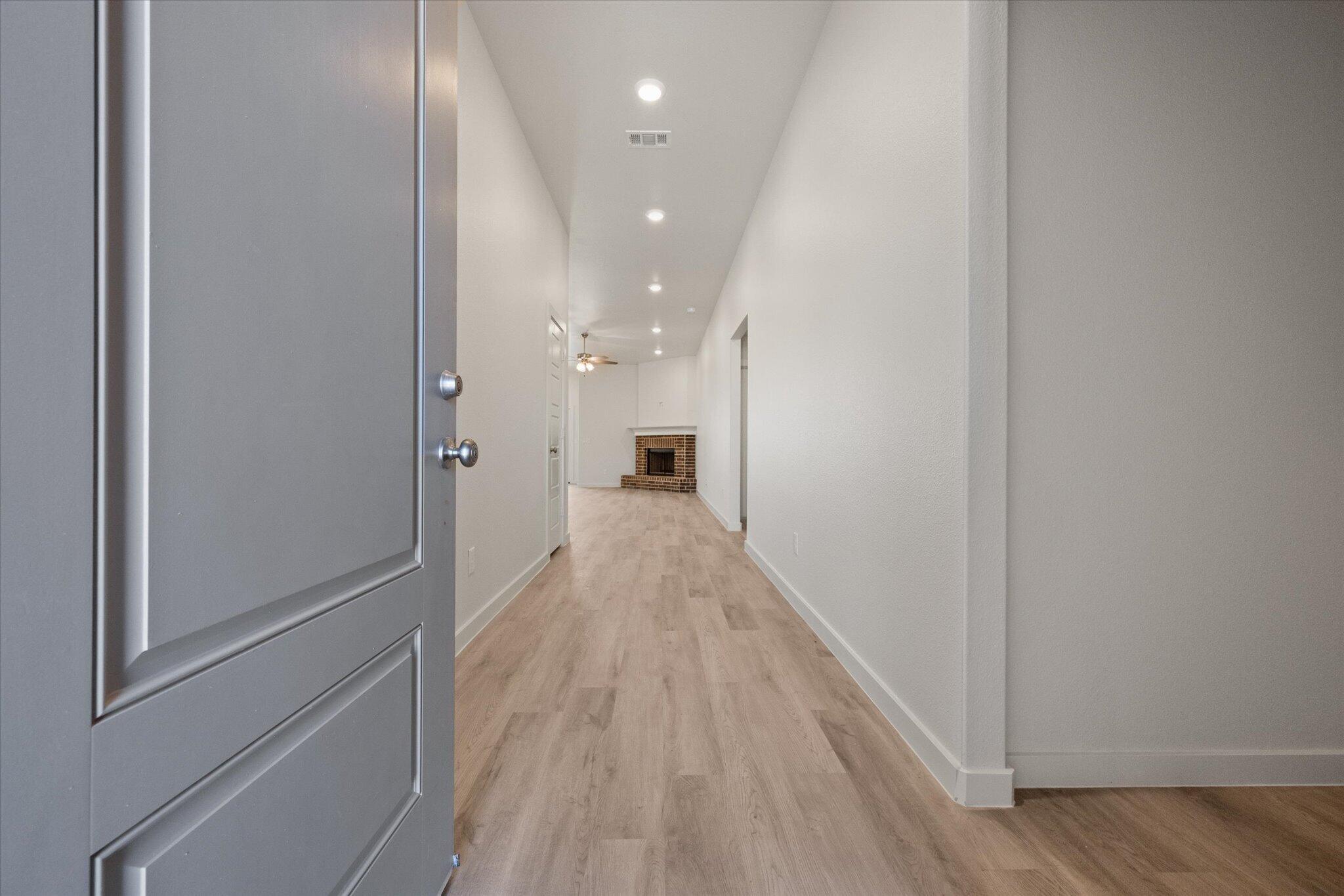 6105 121st Street Lubbock, TX 79424 - Photo 3 of 24 a view of a hallway with wooden floor and a bathroom
