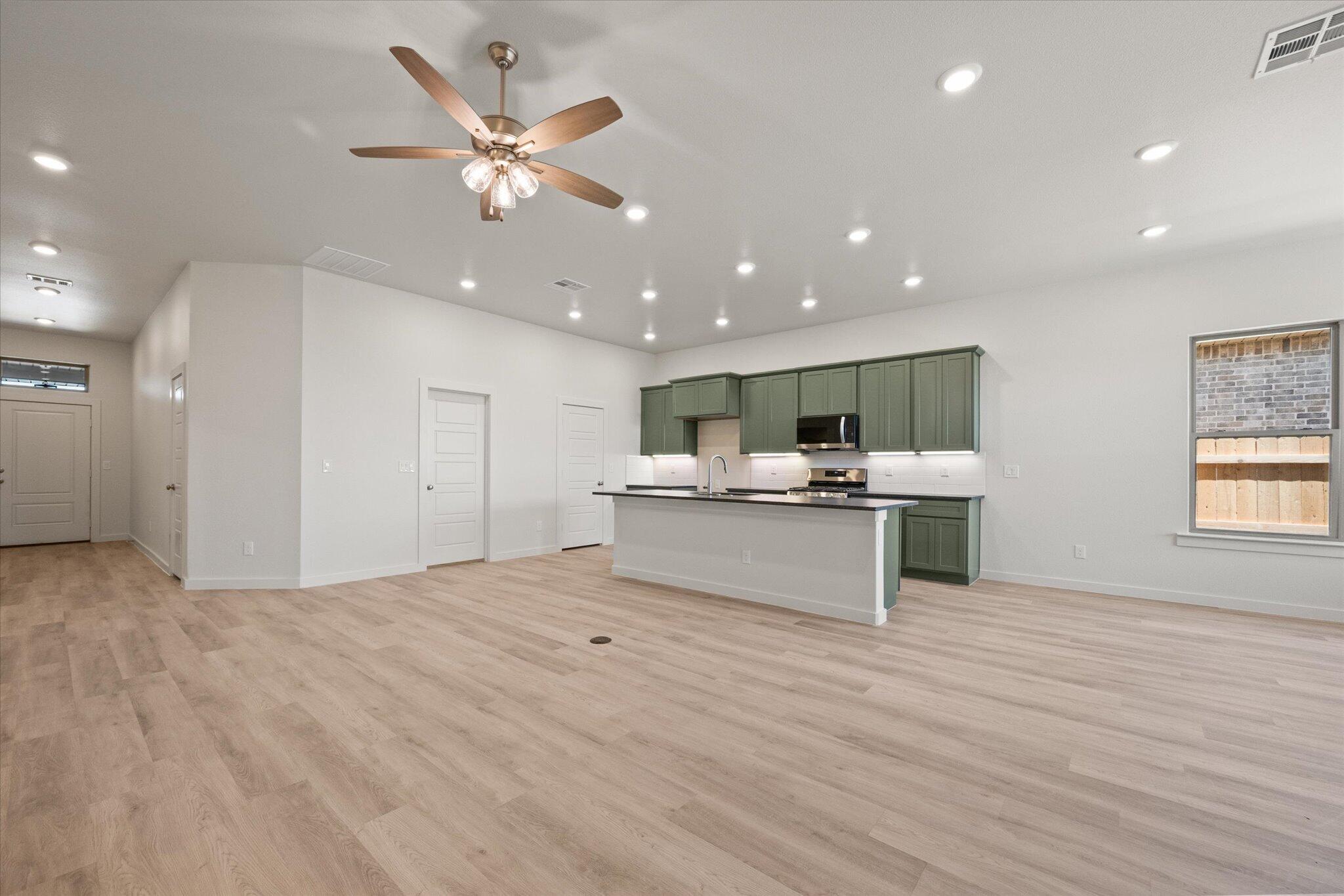 6105 121st Street Lubbock, TX 79424 - Photo 9 of 24 a open kitchen with kitchen island white cabinets and stainless steel appliances