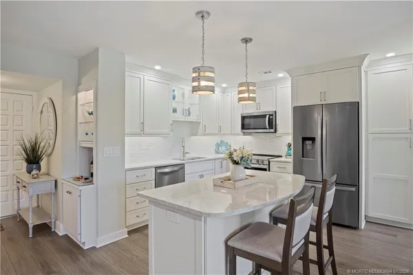a kitchen with stainless steel appliances granite countertop a refrigerator a sink a stove a dining table and chairs