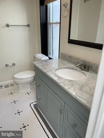 a bathroom with a granite countertop sink a mirror and toilet