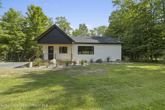 a front view of house with yard and trees in the background