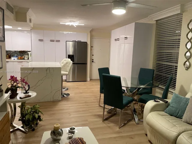 a living room with couches kitchen view and a refrigerator