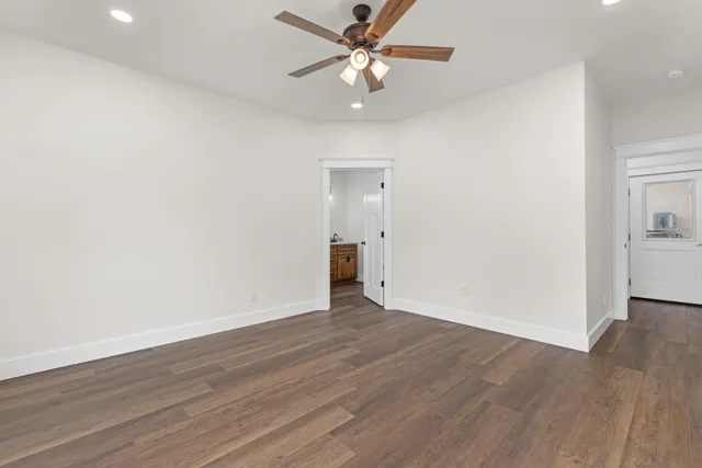 an empty room with wooden floor and a ceiling fan