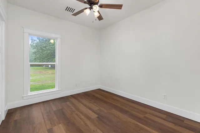 an empty room with a window and wooden floor