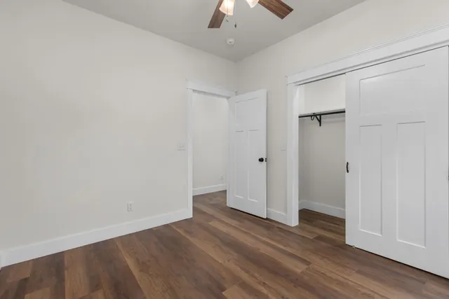 an empty room with wooden floor and a ceiling fan