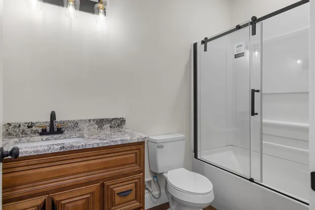 a bathroom with a granite countertop sink toilet and shower