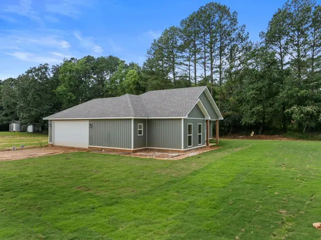 a white house with a big yard and large trees